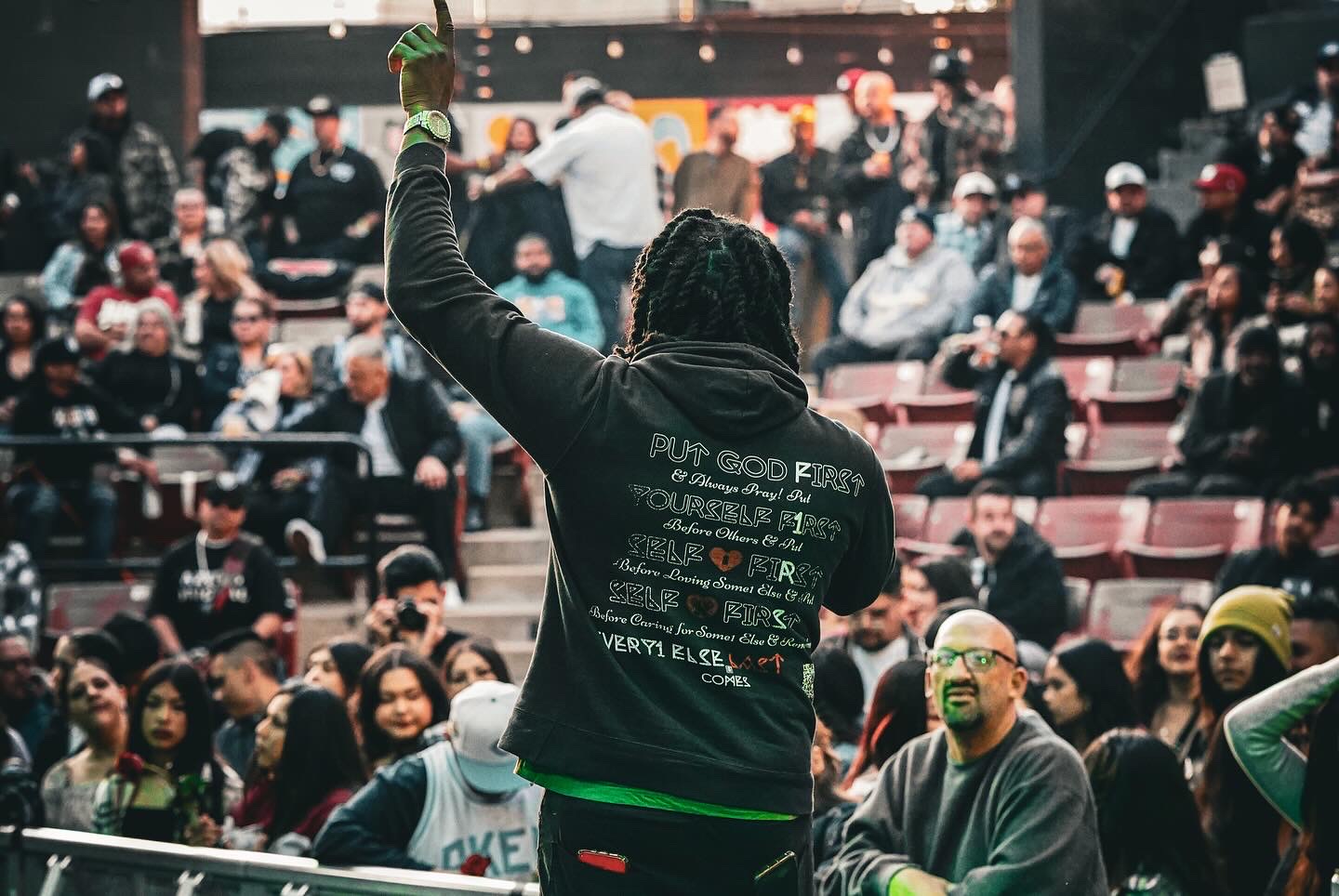 JoethePoet raising his hand while performing before a packed amphitheater